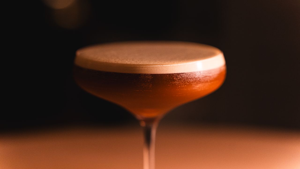 Detalhe de cocktails coloridos servidos ao balcão de um bar noturno em Lisboa