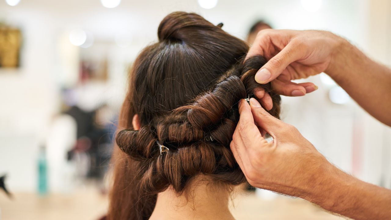 Profissional de beleza a pentear e a fazer styling do cabelo de uma cliente num salão de Lisboa