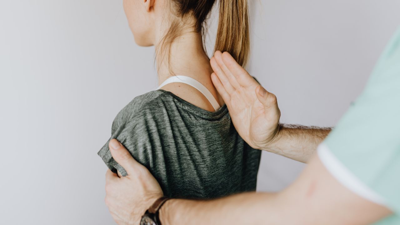 Quiroprático a explicar a um paciente um modelo da coluna vertebral numa clínica de Lisboa
