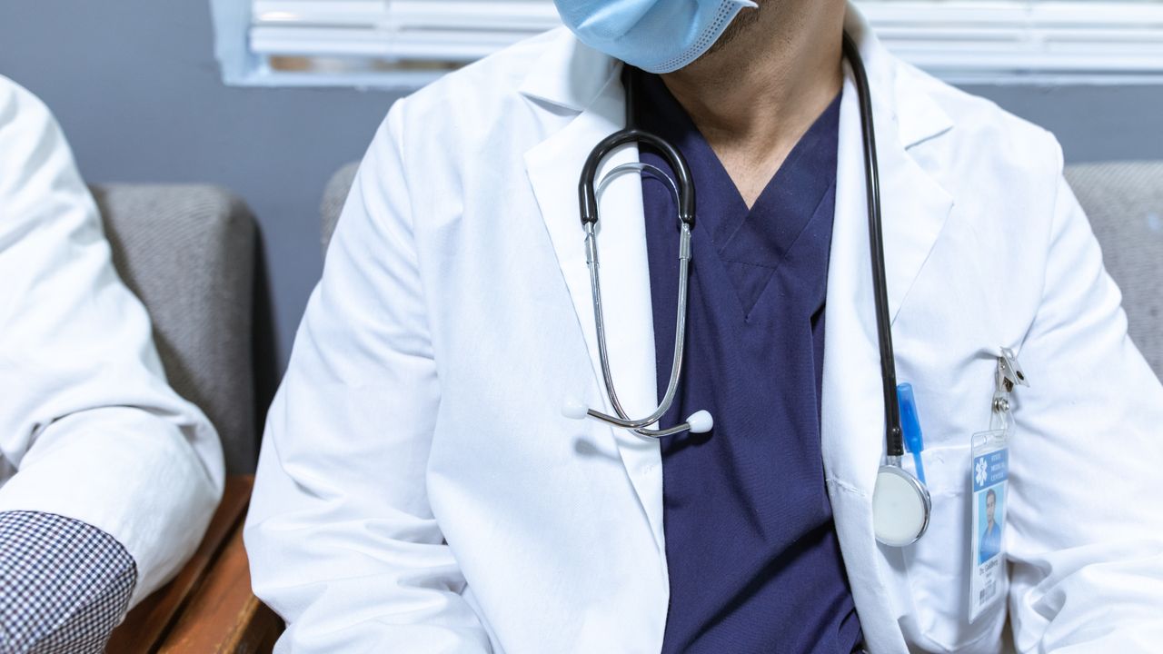 Médico sorridente a receber um paciente à entrada de uma clínica em Lisboa