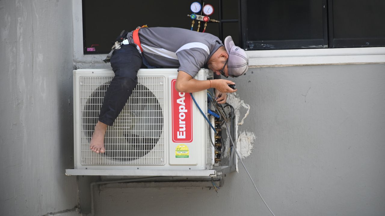 Técnico de AVAC a instalar uma unidade de ar condicionado num edifício em Lisboa
