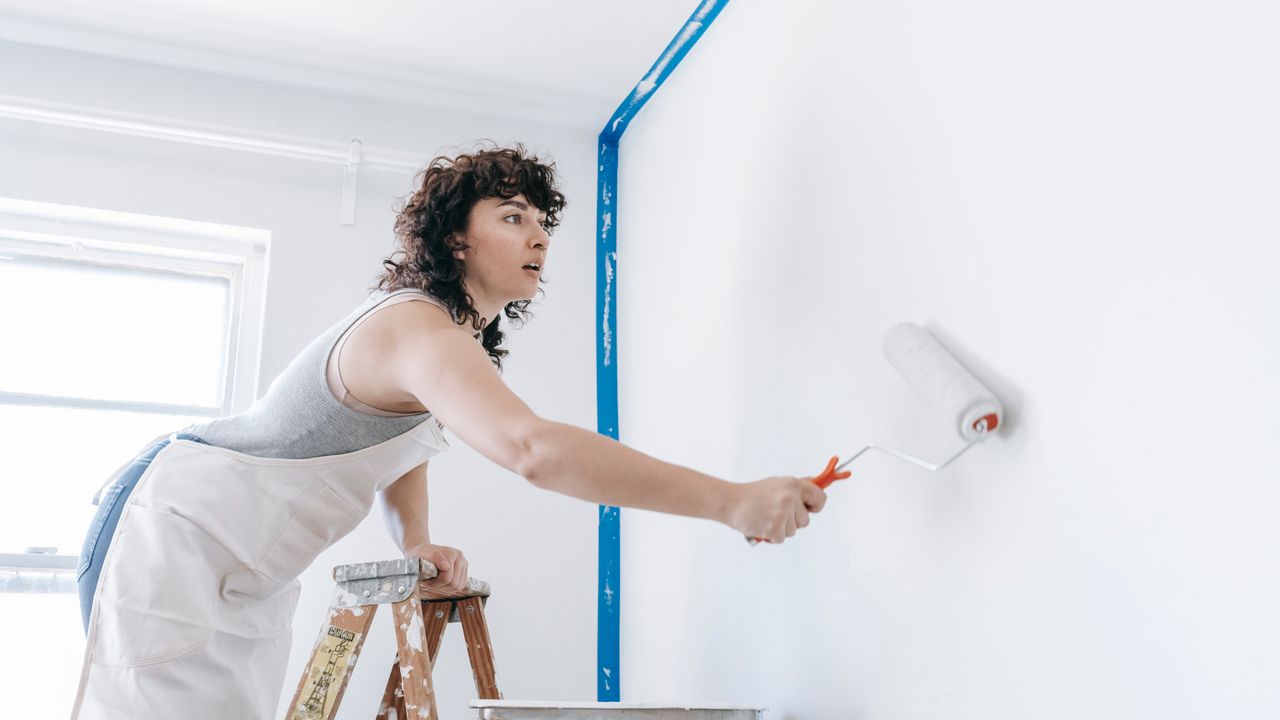 Pintor profissional a pintar a parede de uma casa em Lisboa