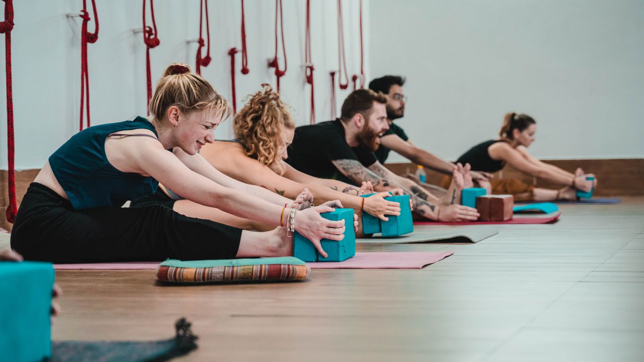 Grupo em prática de Yoga sobre tapetes num estúdio de bem-estar em Lisboa