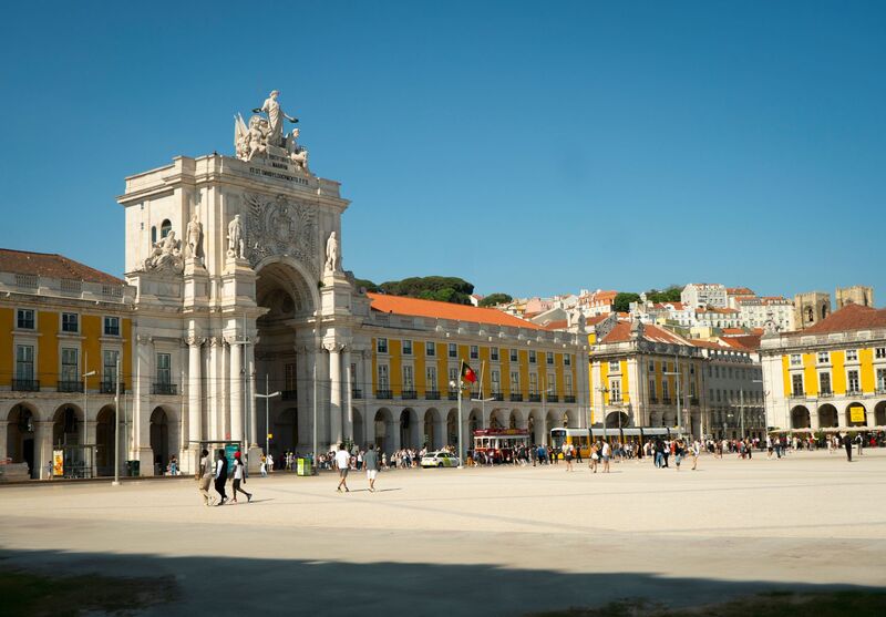 Praça histórica na Baixa de Lisboa com arquitetura pombalina e turistas